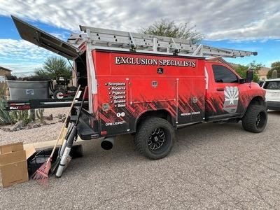 An Executive Pest Control service truck is equipped with tools and labeled "Exclusion Specialists," highlighting their expertise in pest control. The vehicle displays a list of targeted pests, including scorpions, rodents, and pigeons, emphasizing the c
