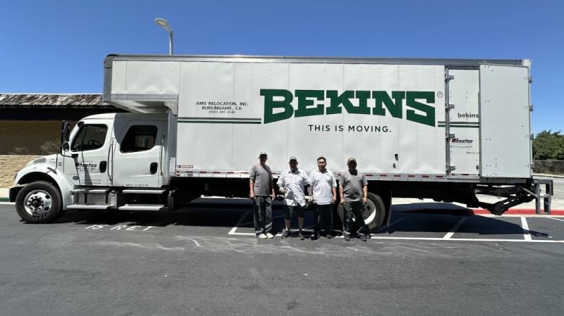 A Bekins moving truck from AMS Relocation, Inc. (Burlingame, CA) is parked outdoors, with four movers posing in front, showcasing their professional relocation services.