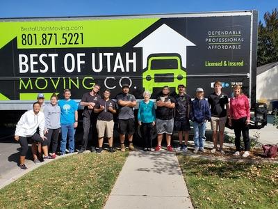 The team from Best of Utah Moving Company stands proudly in front of a branded moving truck, joined by customers in a residential neighborhood. The image highlights the company's professionalism, community focus, and commitment to dependable moving servi