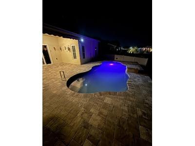 A professionally designed backyard pool installation illuminated at night, showcasing the craftsmanship of Hawaiian Island Pools.