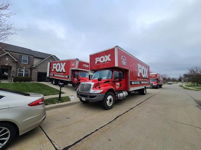 Three Fox Moving and Storage trucks are lined up in a residential neighborhood, actively handling a large-scale home move.