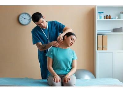 An image of a practitioner in blue scrubs performing a gentle neck adjustment on a seated female patient, showcasing the patient-centered care provided at Haycock Chiropractic. The clean treatment room setting highlights the professional and restorative c