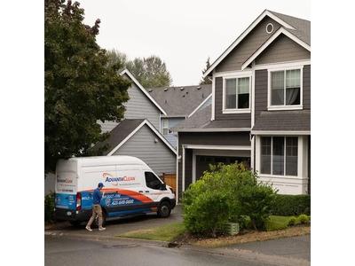 An image of a technician walking toward a branded service van parked in a residential driveway, showcasing the prompt home visits offered by AdvantaClean of Metro New Orleans. The professional fleet vehicle parked outside a two-story house highlights the