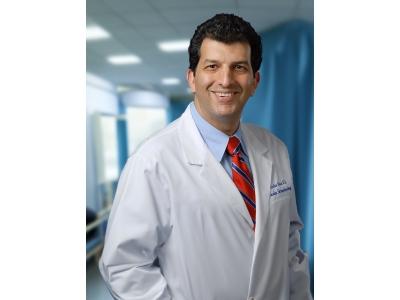 Dr. Arshia M. Noori, MD, an experienced physician, is pictured in a professional white coat, standing in a medical setting, reflecting his dedication to patient care and medical excellence.