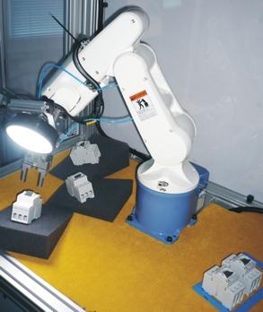 The robot is equipped with a gripper and one camera in the center of the ring lighting. The image processing software exactly detects any 3D poses and orientations of objects and subsequently controls their sorted placement.