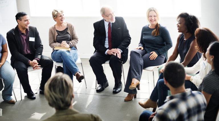 A diverse group of employees sitting in a circle participating in an interactive workplace diversity training program and group di
