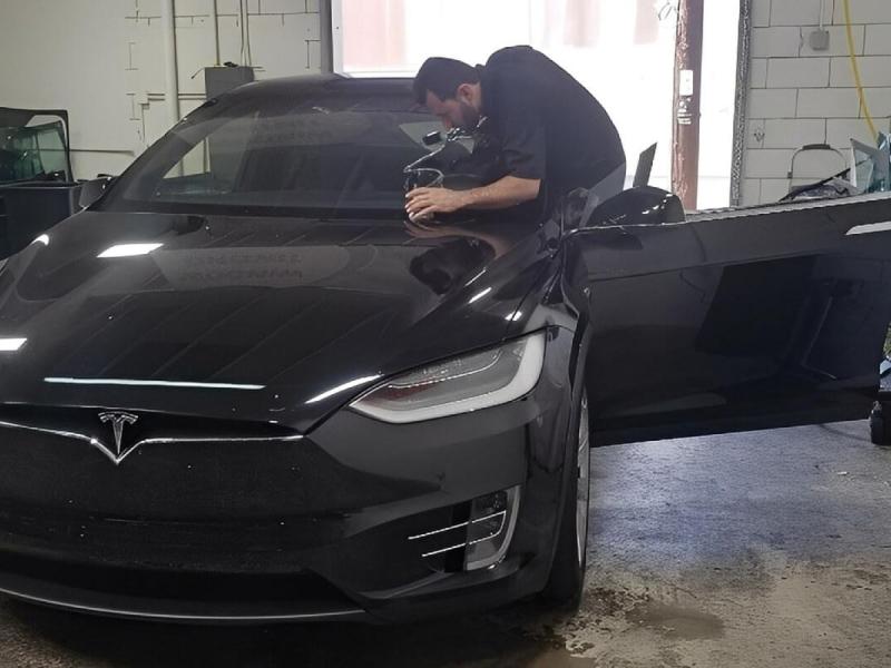 AMB Auto Glass and Window Tint technician working on a Tesla at the company's San Diego shop