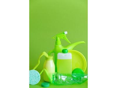 A collection of green cleaning supplies, including spray bottles, sponges, and detergent containers, arranged against a matching green background, emphasizing eco-friendly and coordinated cleaning products.