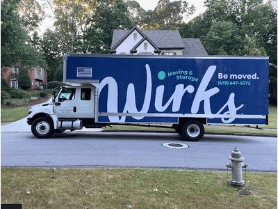 A large blue Wirks Moving & Storage truck parked in a suburban neighborhood, with the company name and contact info prominently displayed on the side.