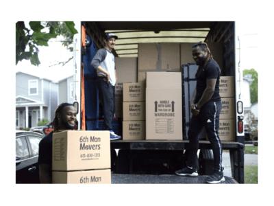 The image shows 6th Man Movers team members loading a truck with labeled boxes, showcasing their teamwork and positive energy during a move.