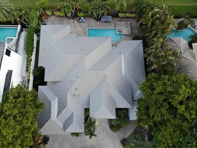 Aerial view of a residential property showcasing a newly installed, modern metal roof by Proper Roofing Inc., designed to provide both durability and style while complementing the surrounding landscape.
