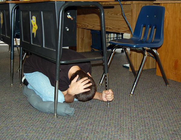 A child at the Hillsides Education Center drops,covers and holds on during the Great California Shake Out drill.